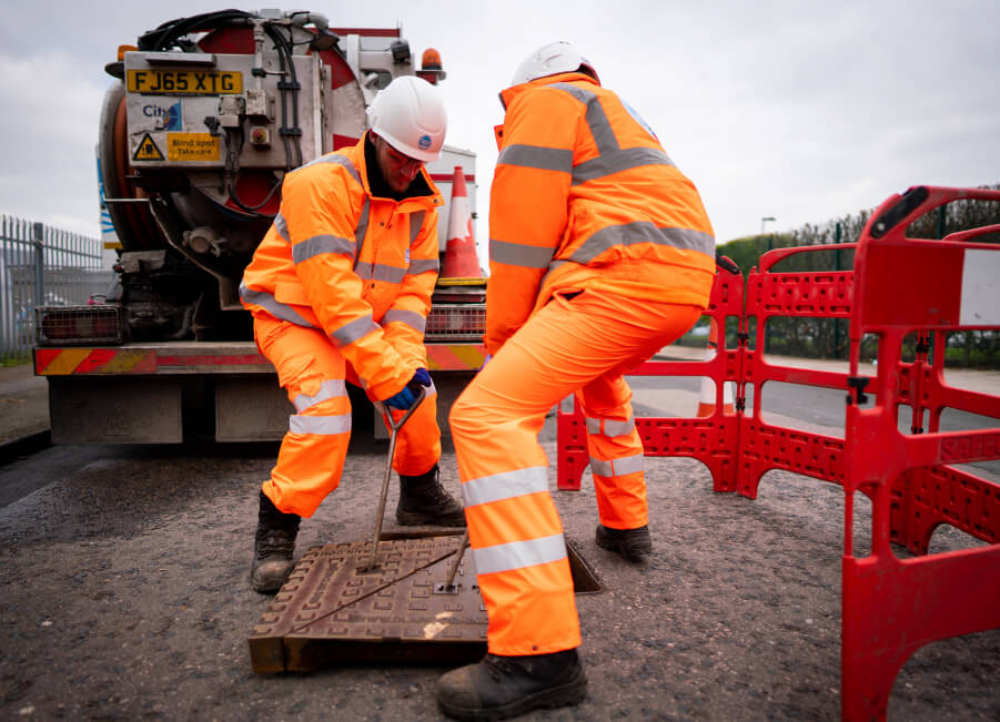 Two people lifting a drain