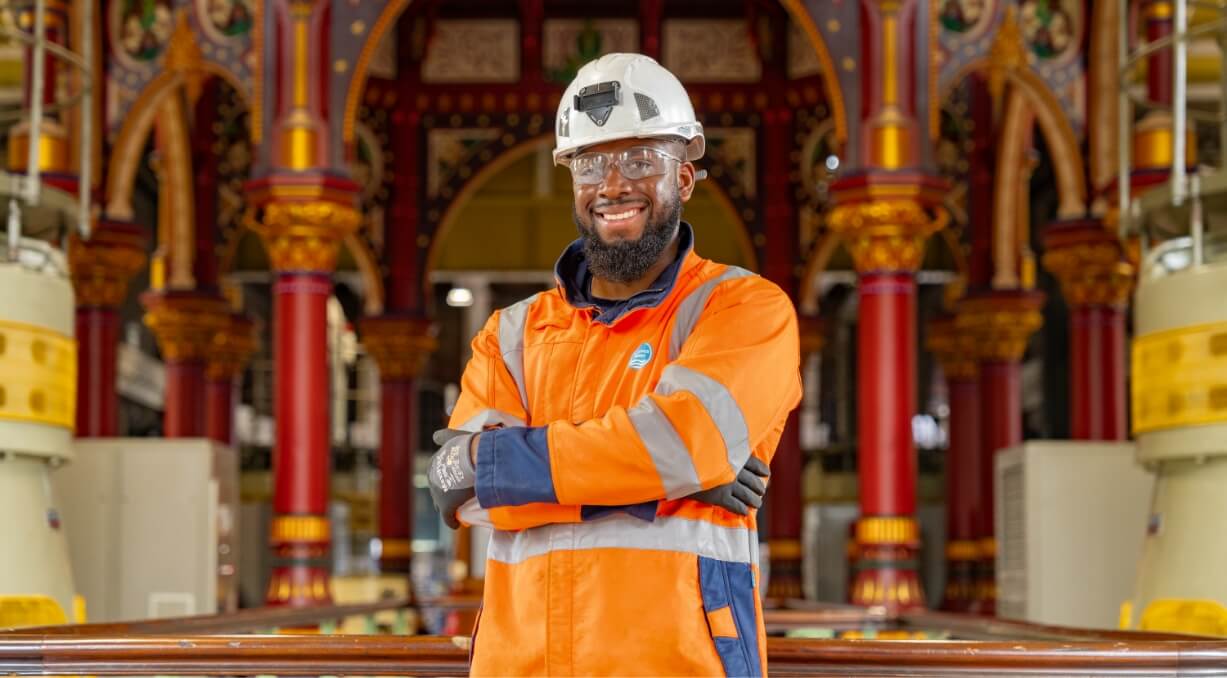Person in hardhat with arms crossed smiling