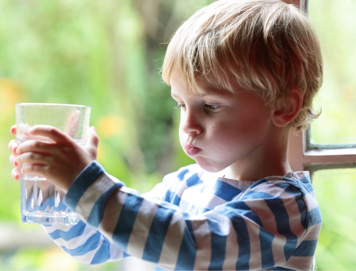 Young child drinking water from a glass