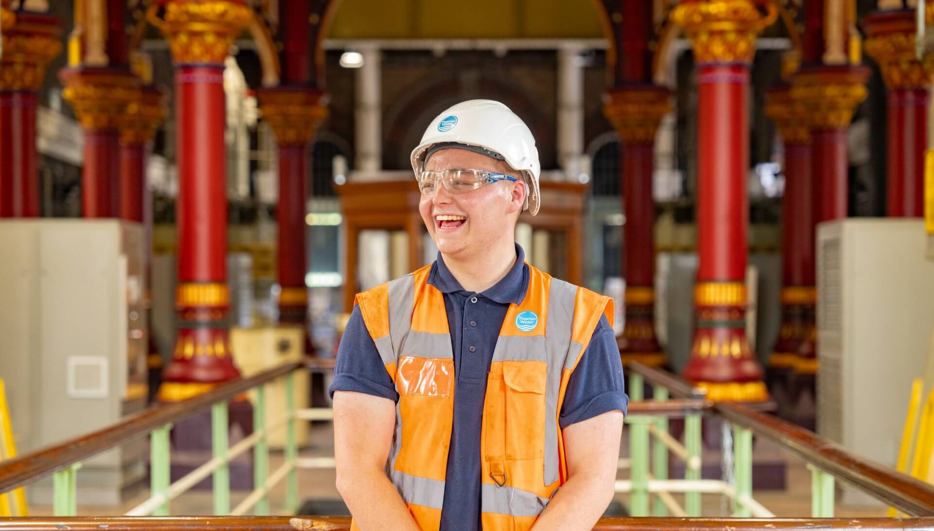 Person with hardhat smiling in facility