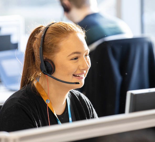 a customer agent smiles while speaking to a customer on the phone