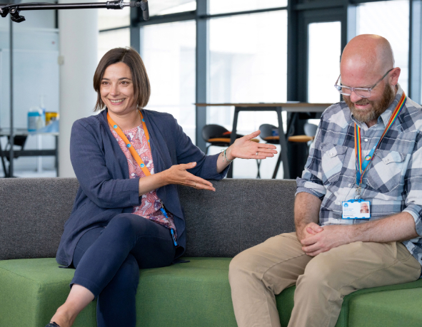 two colleagues laughing while having a conversation on the couch