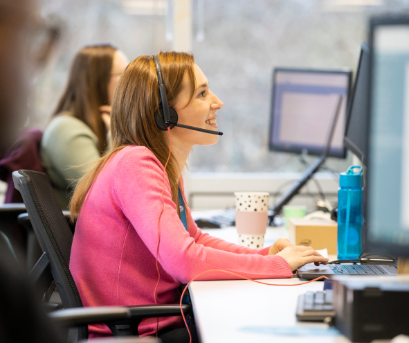 a customer agent smiles while speaking to customer on the phone