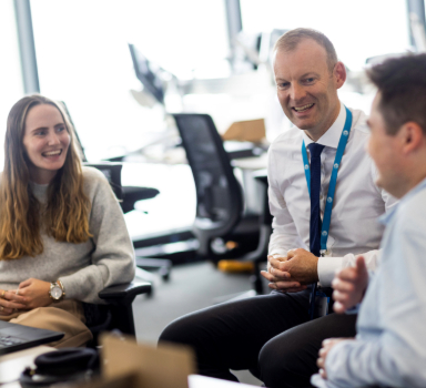 three colleagues smile working together in the office