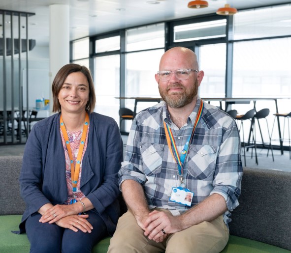 Two Thames Water colleagues smile while sitting on an office sofa